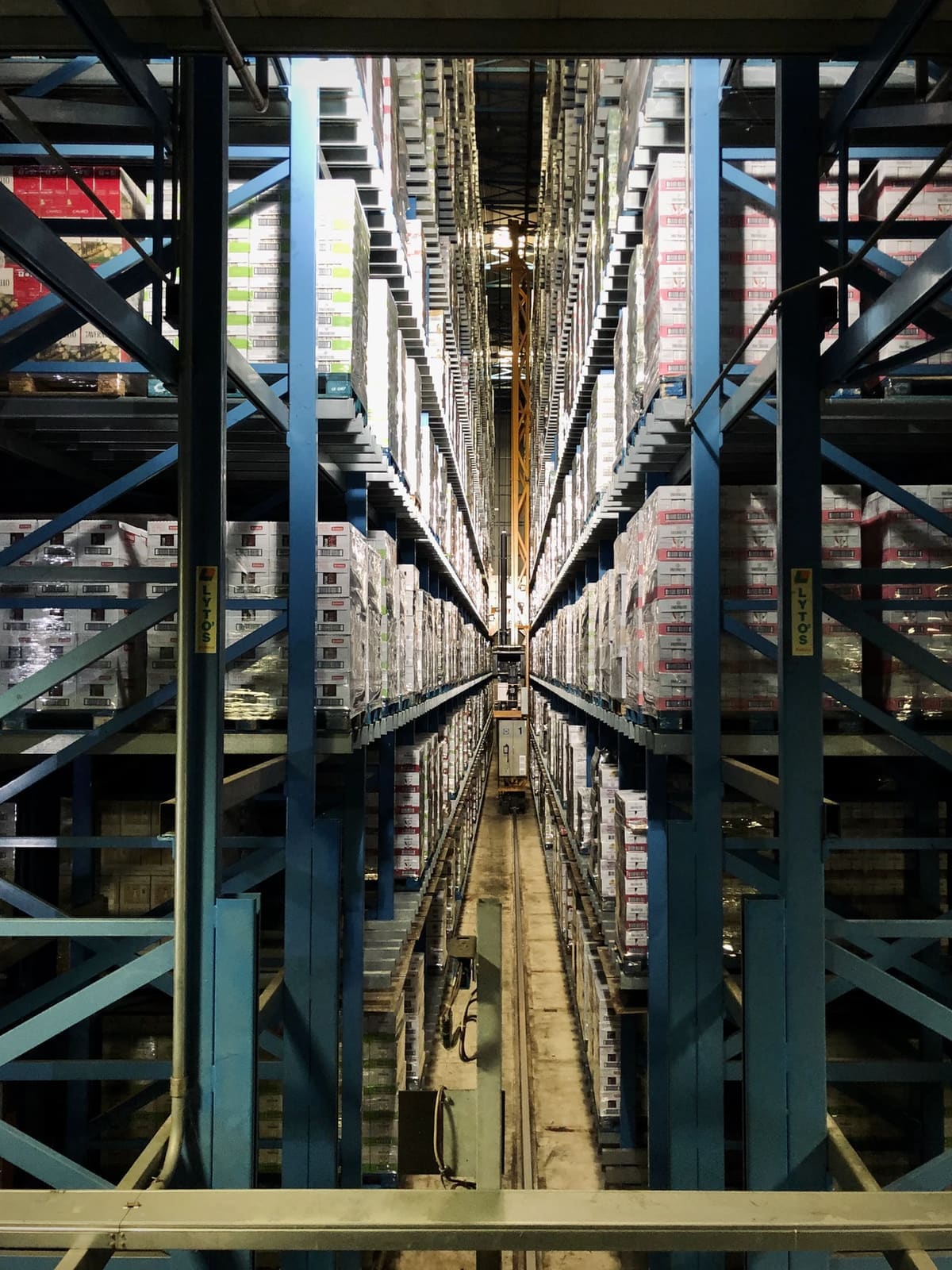 A high-bay warehouse aisle stacked with cases of stock