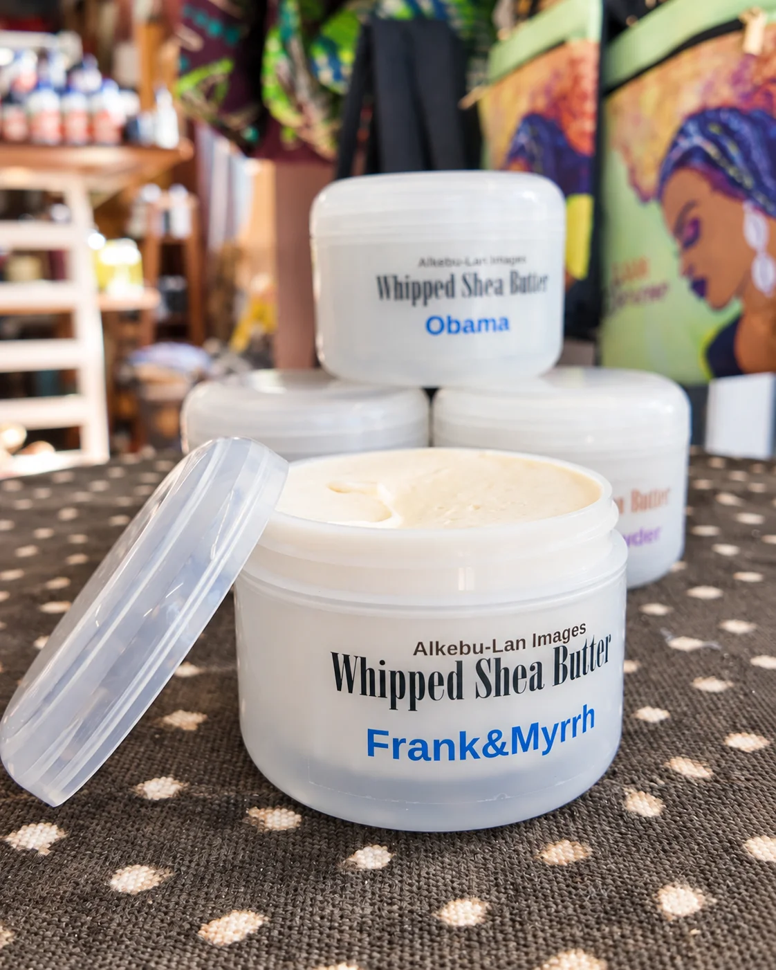 An open Frank & Myrrh whipped shea butter jar showing the butter’s texture, with its lid resting alongside